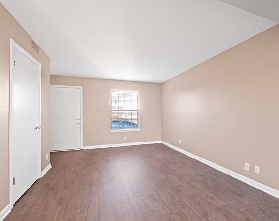 an empty living room with wood floors and a window