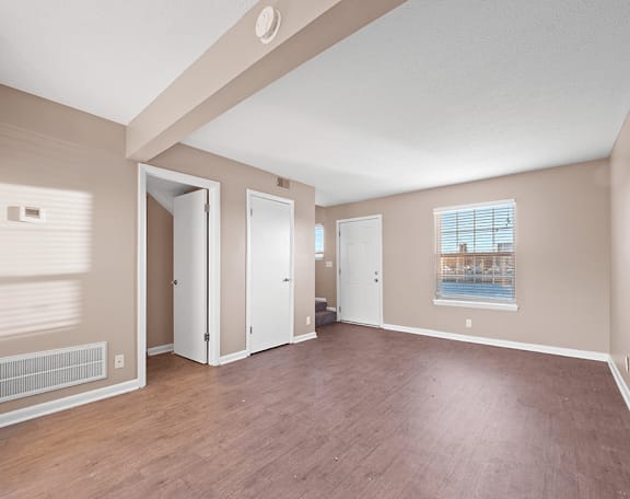 an empty living room with wood flooring and a window