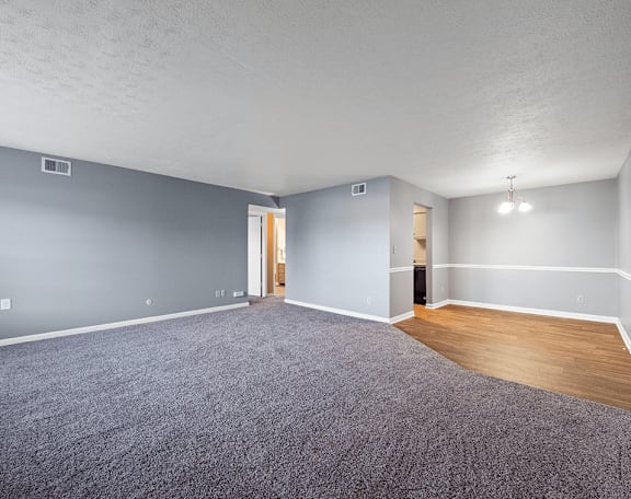 an empty living room with gray carpet and wood flooring