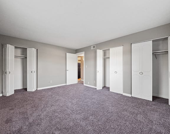 an empty bedroom with closet doors and carpeting