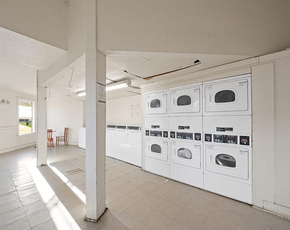 a row of white washers and dryers in a white room with white walls