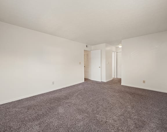 an empty living room with carpet and white walls
