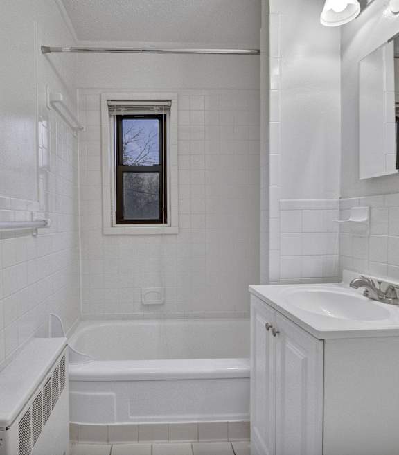 A white bathroom with a tub, sink, and mirror.