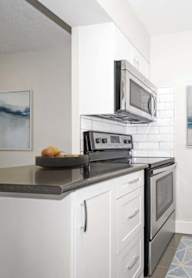 A kitchen with white cabinets and a black counter top.