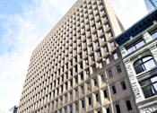 Thumbnail 1 of 7 - A tall building with a grid-like pattern on the side.