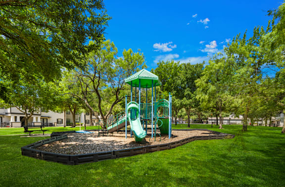 A playground with a green slide and a green roofed structure.