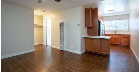 an empty living room and kitchen with a ceiling fan