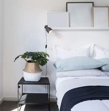 a bedroom with a bed with blue pillows and a plant