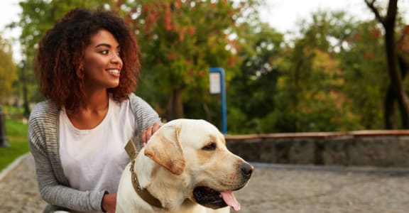 a woman and her dog in a park at The Venue at Orange Apartments, California, 92373