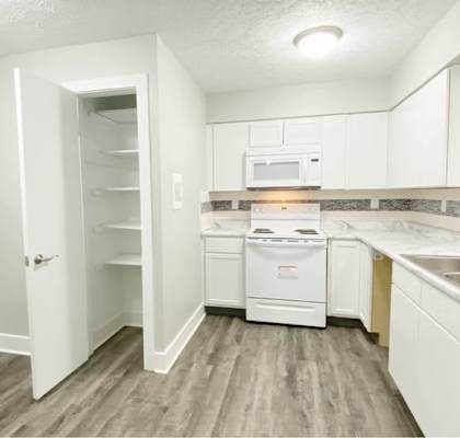 A kitchen with white appliances and cabinets.