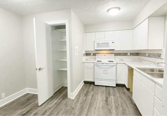 A kitchen with white appliances and cabinets.