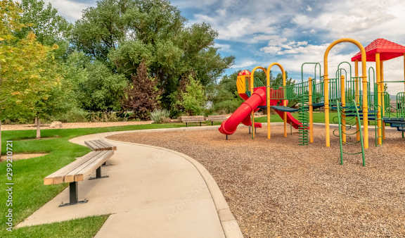 A playground with a red slide and green and yellow play equipment.