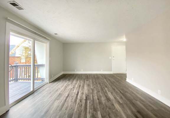 A room with wooden flooring and a sliding glass door.