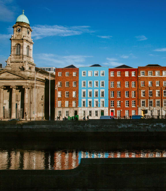 people walking along a canal in front of colorful buildings