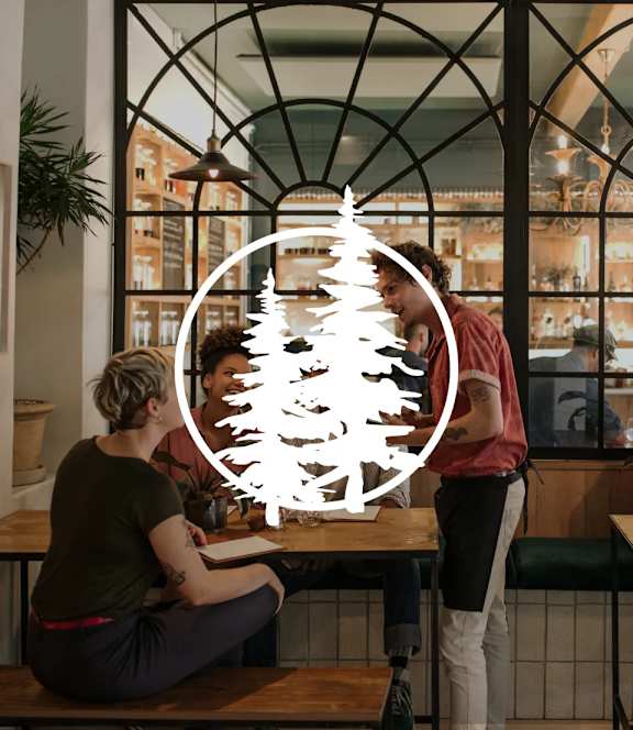A man and a woman are sitting at a table in a restaurant with a large window behind them.