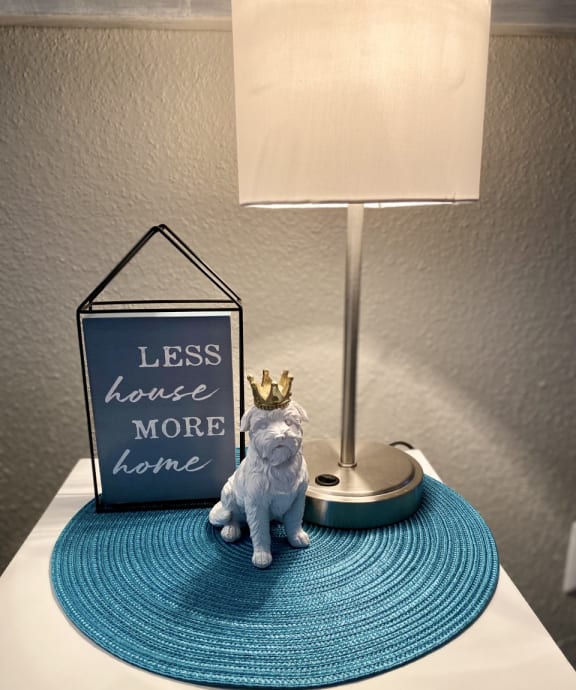 a bedside table with a lamp and a small dog with a crown on it