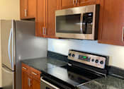 Thumbnail 19 of 23 - A kitchen with a stove, refrigerator, and microwave.