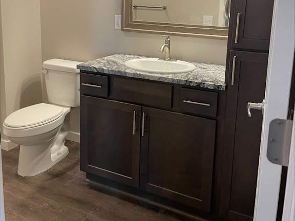 A bathroom with a toilet, sink, and mirror.