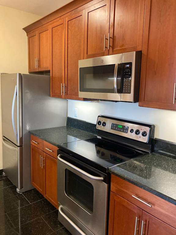 A kitchen with a stove, refrigerator, and microwave.