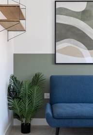 a bedroom with a bed and a nightstand with a lamp and a framed picture