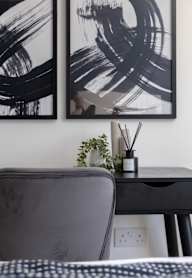 a bedroom with a bed and a nightstand with a lamp and a framed picture