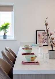 a dining room with a wooden table and blue chairs and a blue wall with artwork
