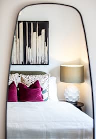 a bedroom with a bed and a nightstand with a lamp and a framed picture