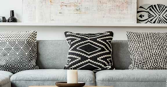 A grey couch with a wooden table in front of it and a painting on the wall.