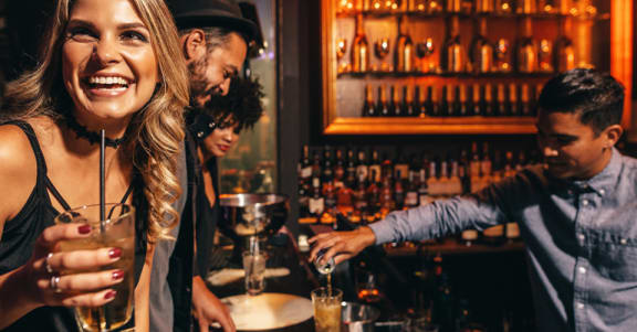 a bartender pouring a drink for a woman at a bar at The Venue at Orange Apartments, California, 92373