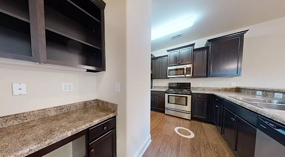 A kitchen with a granite counter top and dark brown cabinets. at The Villas at Nature Walk, Huntsville, Alabama