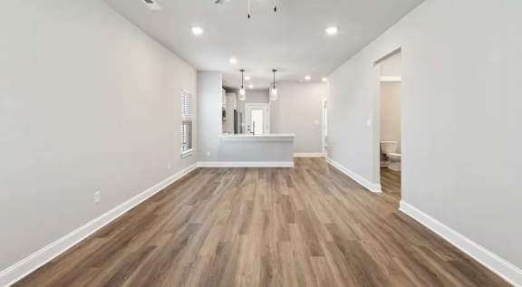 A modern kitchen with white cabinets and a wooden floor. at Ovation at Town Madison, Madison, 35758