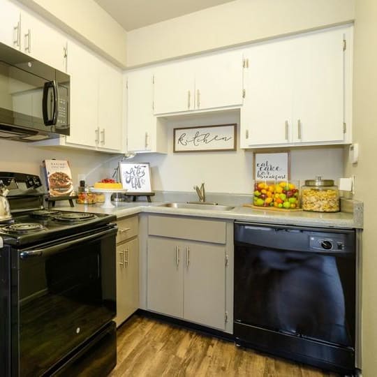 a kitchen with white cabinets and black appliances