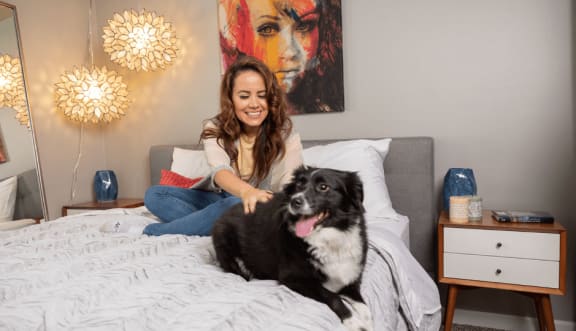 Woman Sitting On A Bed With Dog at The View Apartments St Charles, St Charles