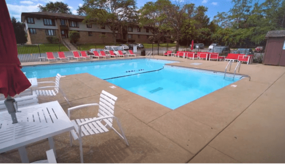 a swimming pool with chairs and tables around it  at The Clarendon Apartment Homes, Clarendon, Illinois