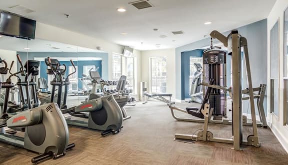 a gym with cardio equipment and a tv  at The Mark Apartments, Glendale Heights, Illinois