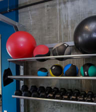 a row of bowling balls on a shelf in a gym