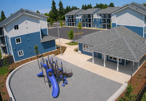 A playground area with a blue slide is surrounded by apartment buildings.