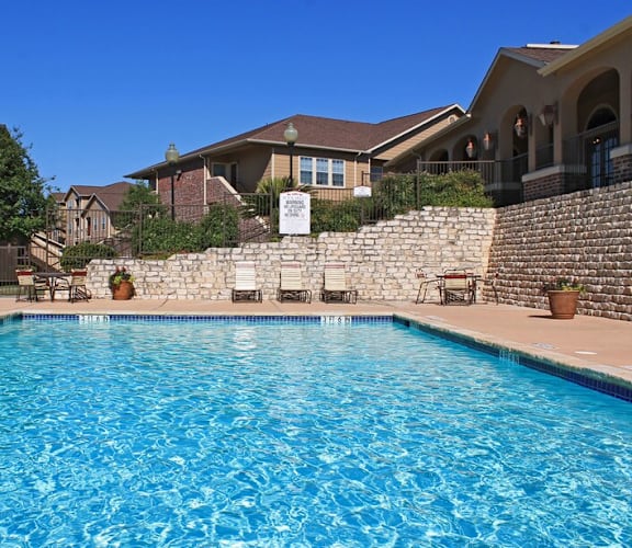 A swimming pool in a residential area with houses and trees in the background.