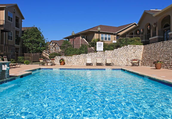 A swimming pool in a residential area with houses and trees in the background.