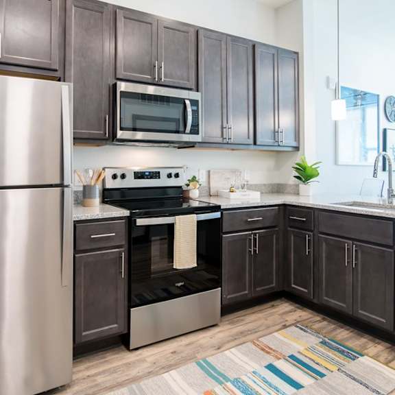 A modern kitchen with dark brown cabinets and stainless steel appliances.