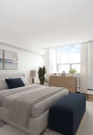 A bedroom with a large bed and a nightstand with a lamp.