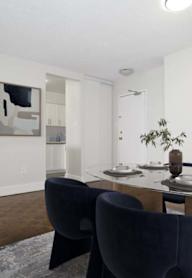 A dining room with a table set for two and a blue chair.