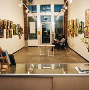 a man sitting in a chair in a room with paintings on the walls