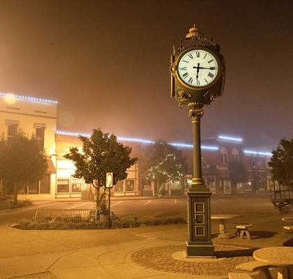 a clock on a pole on a city street