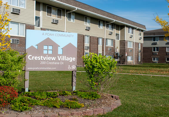 A sign for Crestview Village in front of apartment buildings.