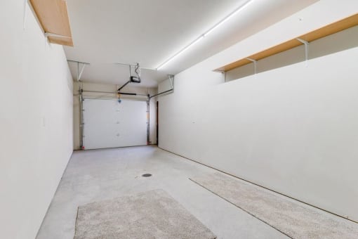 an empty room with a white wall and a white garage door