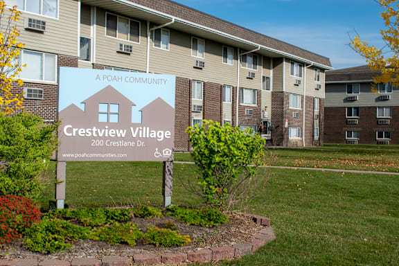 A sign for Crestview Village in front of apartment buildings.