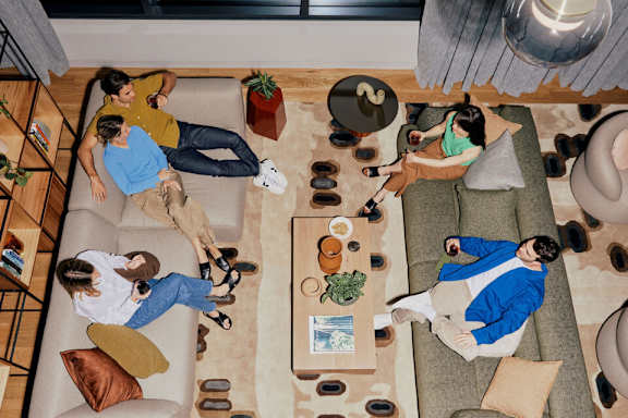 A group of people are sitting and relaxing on a couch in a living room.