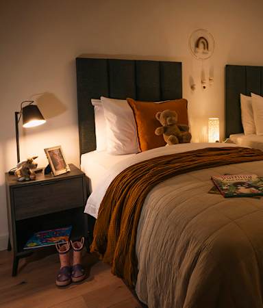 A cozy bedroom with two beds and a nightstand with a lamp.