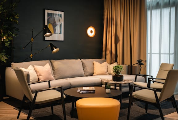 A living room with a grey sofa, a coffee table, and a yellow ottoman.